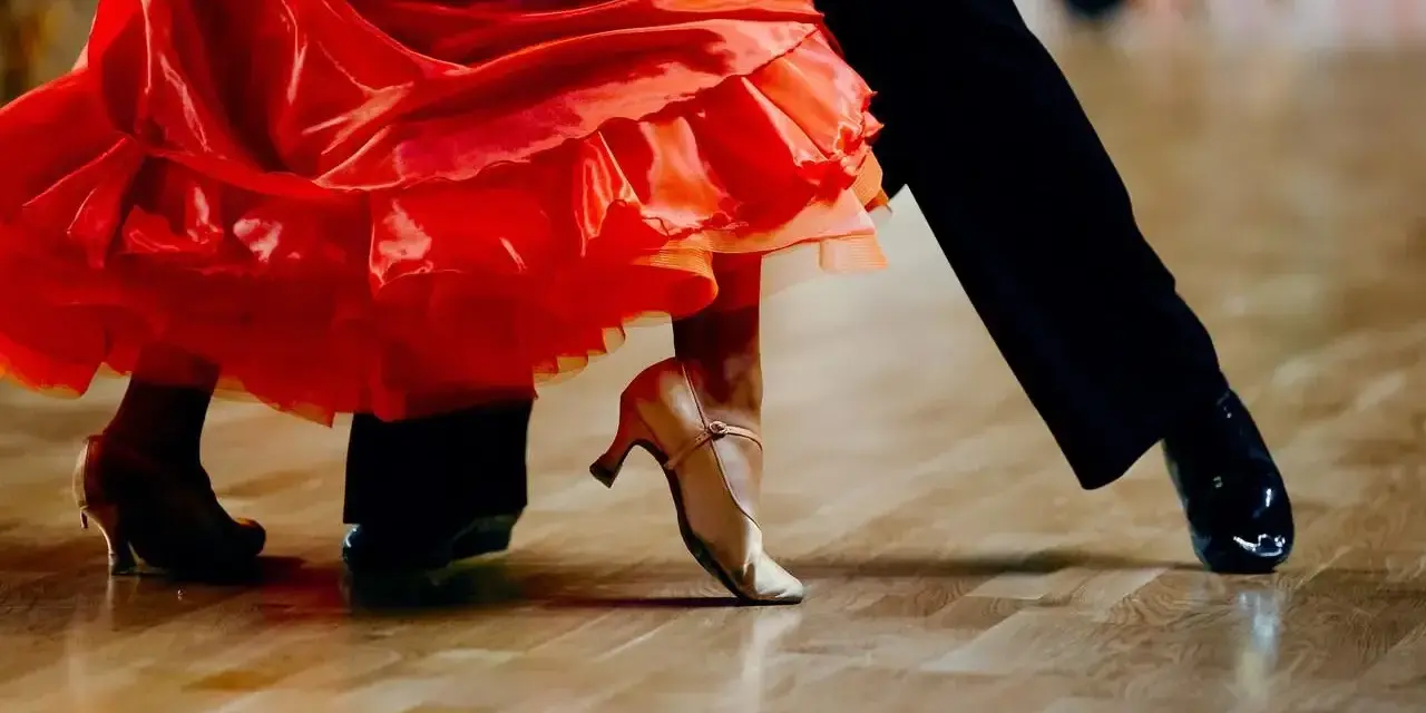 Para tańczy paso doble w rytm muzyki. Czerwona sukienka wiruje, a eleganckie buty poruszają się po parkiecie.