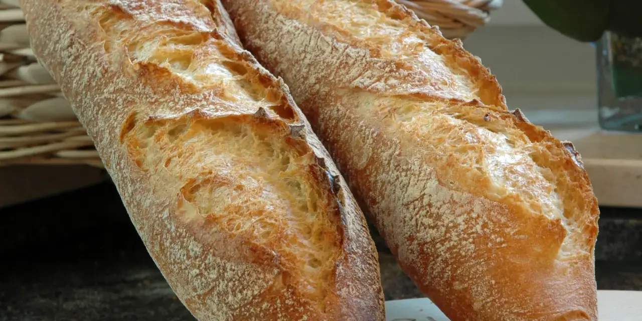 Zwei knusprige Baguettes, eine köstliche t65 Mehl Alternative, liegen auf einem Holzbrett.