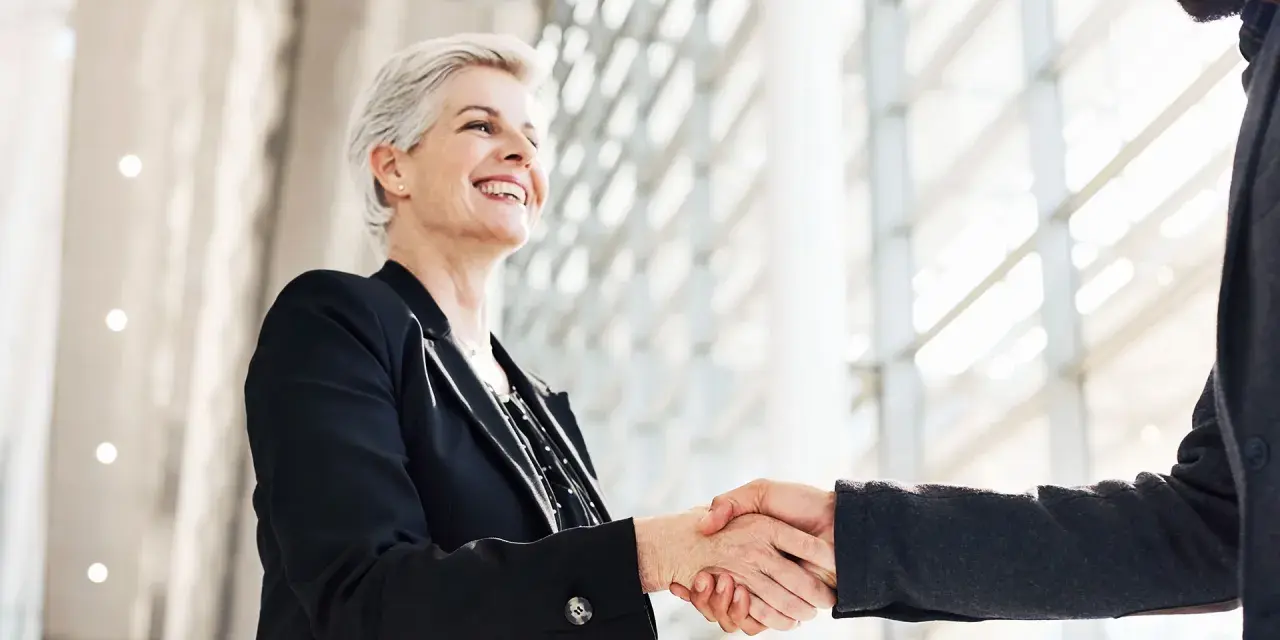 Due professionisti si stringono la mano, un gesto di accordo e fiducia. Sono colleghi raccomandati sul lavoro, pronti a collaborare.
