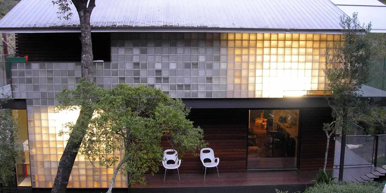 Modern house with a striking glass block installation, bathing the interior in warm light.