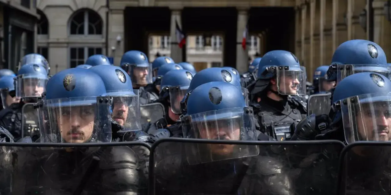 Un grupo de gendarmes con cascos azules y escudos protectores se prepara para mantener el orden frente al Conseil Constitutionnel.