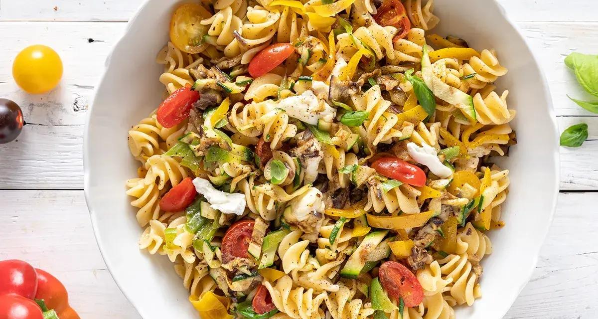 Un piatto colorato di pasta estiva veloce con fusilli, zucchine, peperoni gialli, pomodorini e mozzarella.