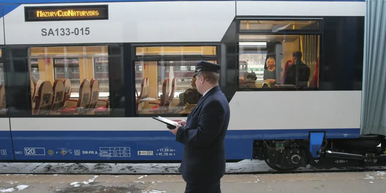 Konduktor sprawdza dane na tablecie. Zastanawiasz się, ile kosztuje bilet u konduktora? Wnętrze pociągu z siedzeniami.