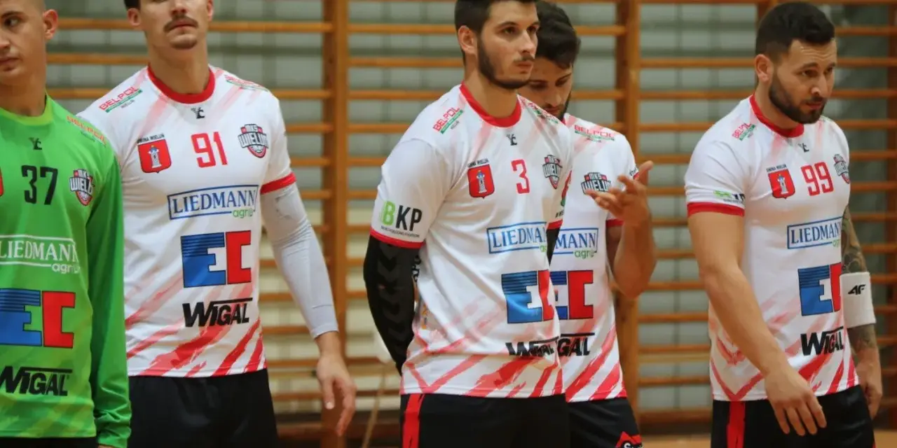 Szymon Kucharski i koledzy z drużyny w białych strojach z czerwonymi detalami, gotowi do gry.