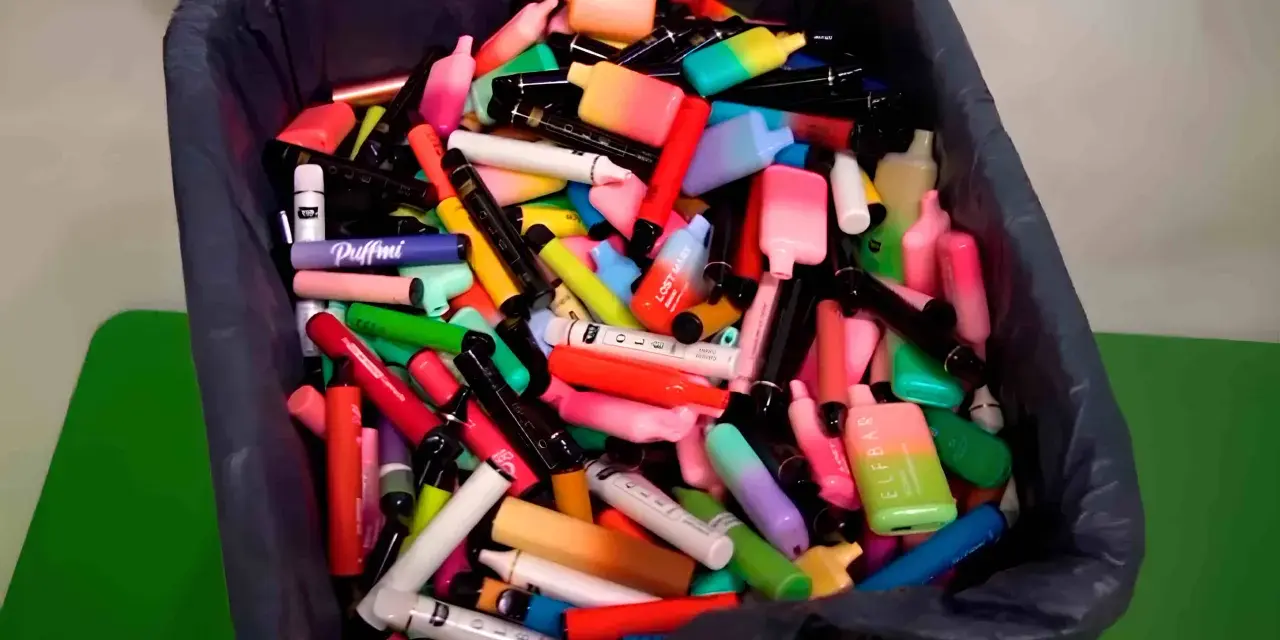 Contenedor lleno de vapes desechables de colores. ¿Qué hacer con un vape desechable? Reciclaje responsable.