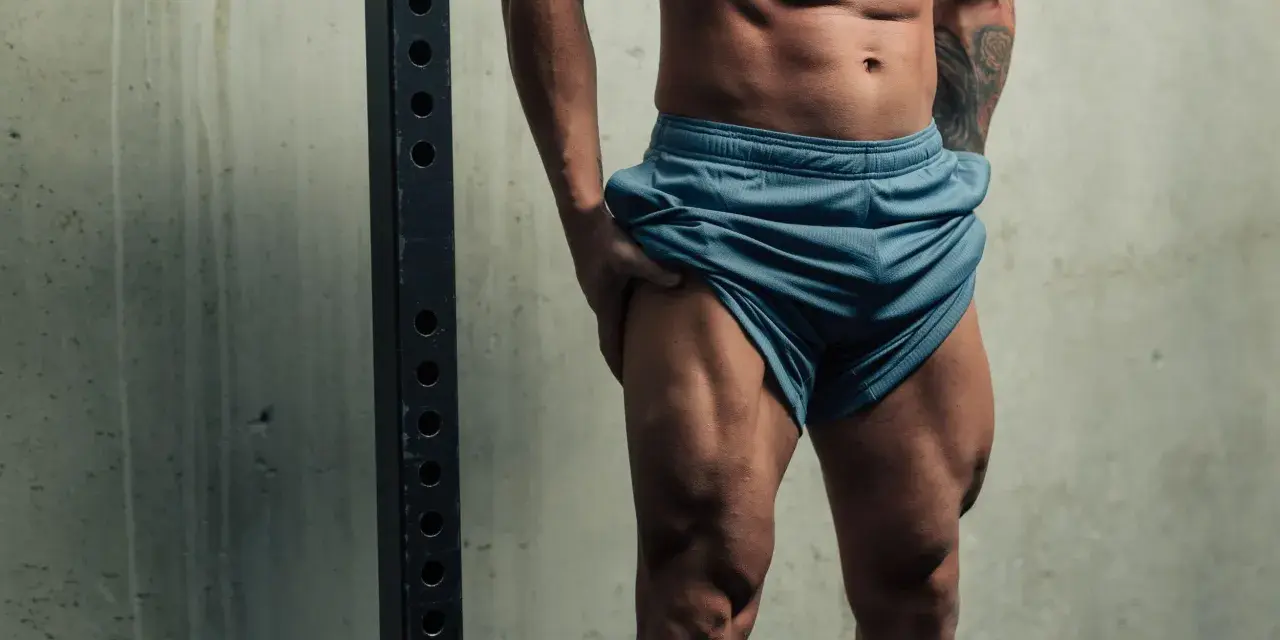 Muskulös person visar upp sina ben på gymmet.