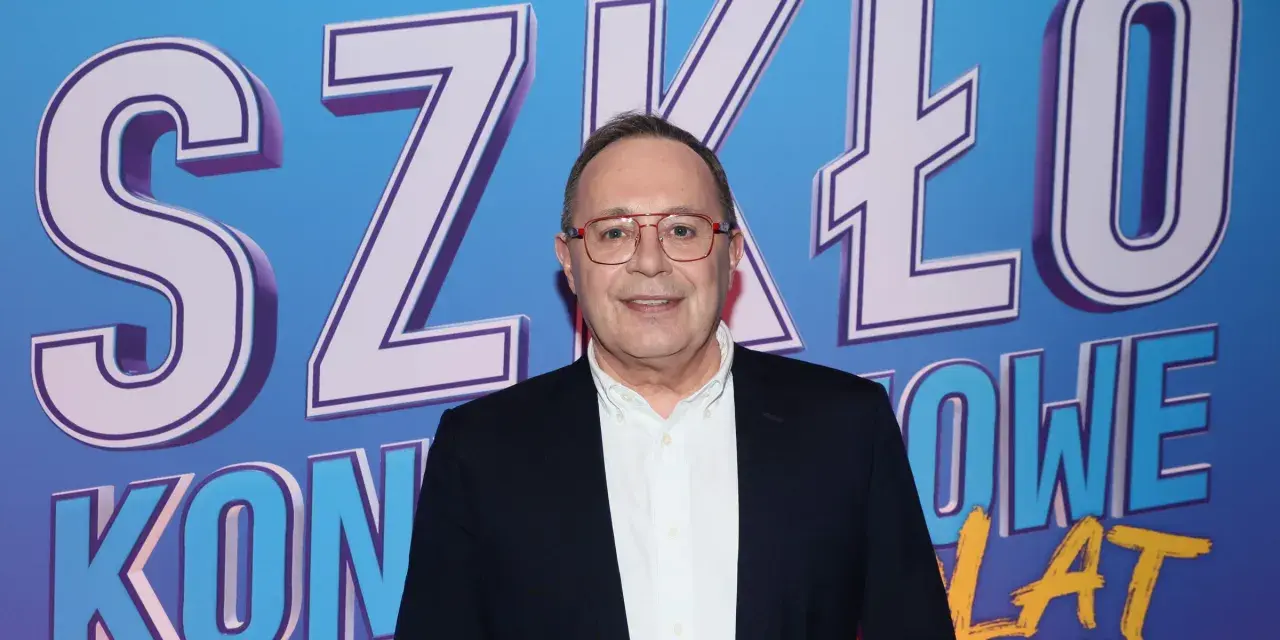 Uśmiechnięty mężczyzna w okularach na tle napisu "SZKŁO KONTAKTOWE OBSADA".