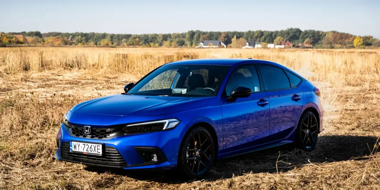 Błękitny Honda Civic 11. generacji na tle jesiennego pola.