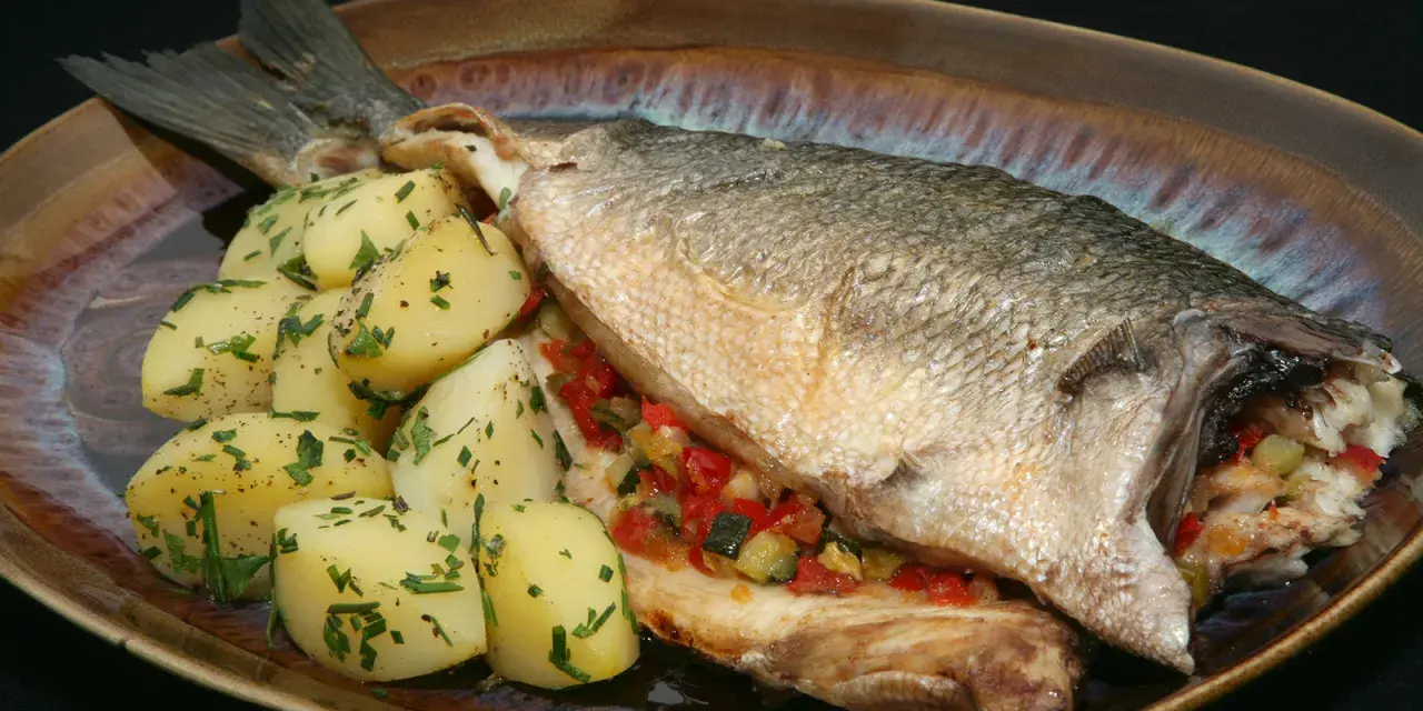 Lubina al horno con verduras y patatas. Un plato principal delicioso y saludable.