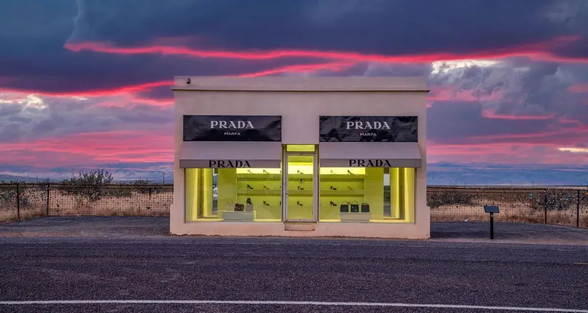 Prada Marfa, une installation artistique isolée au Texas, se dresse sous un ciel crépusculaire aux teintes roses et violettes.