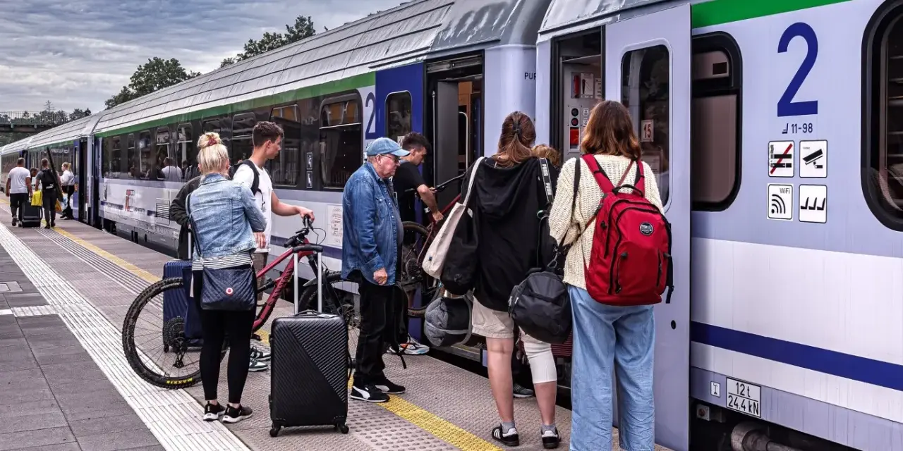 Ludzie z bagażami i rowerami czekają na pociąg PKP. Może właśnie skorzystają ze zniżki PKP na podróż?