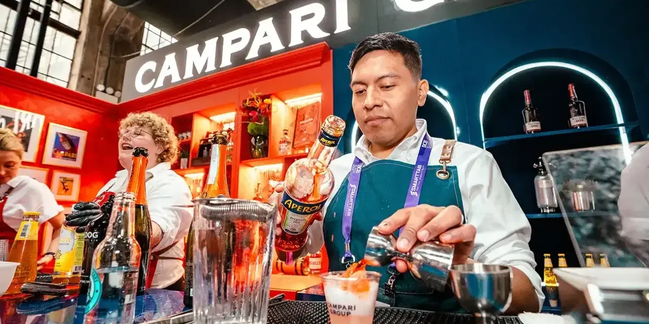 Barman nalewa Aperol do drinka, w tle logo Campari.