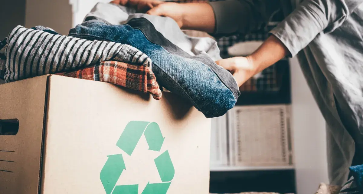 Pudełko z ubraniami i symbolem recyklingu. Wiesz, gdzie można oddać ubrania za darmo?