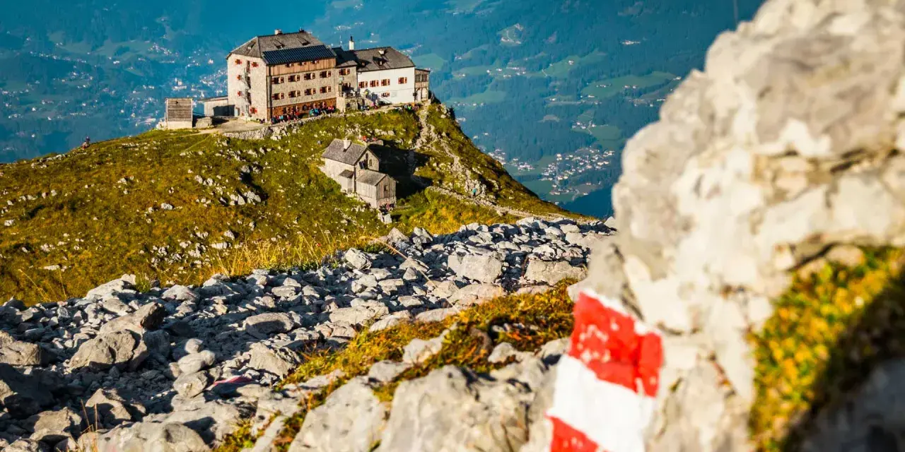 Watzmannhaus Wanderung: Ein markierter Weg führt zu diesem Berggasthof auf einem felsigen Grat mit Blick ins Tal.