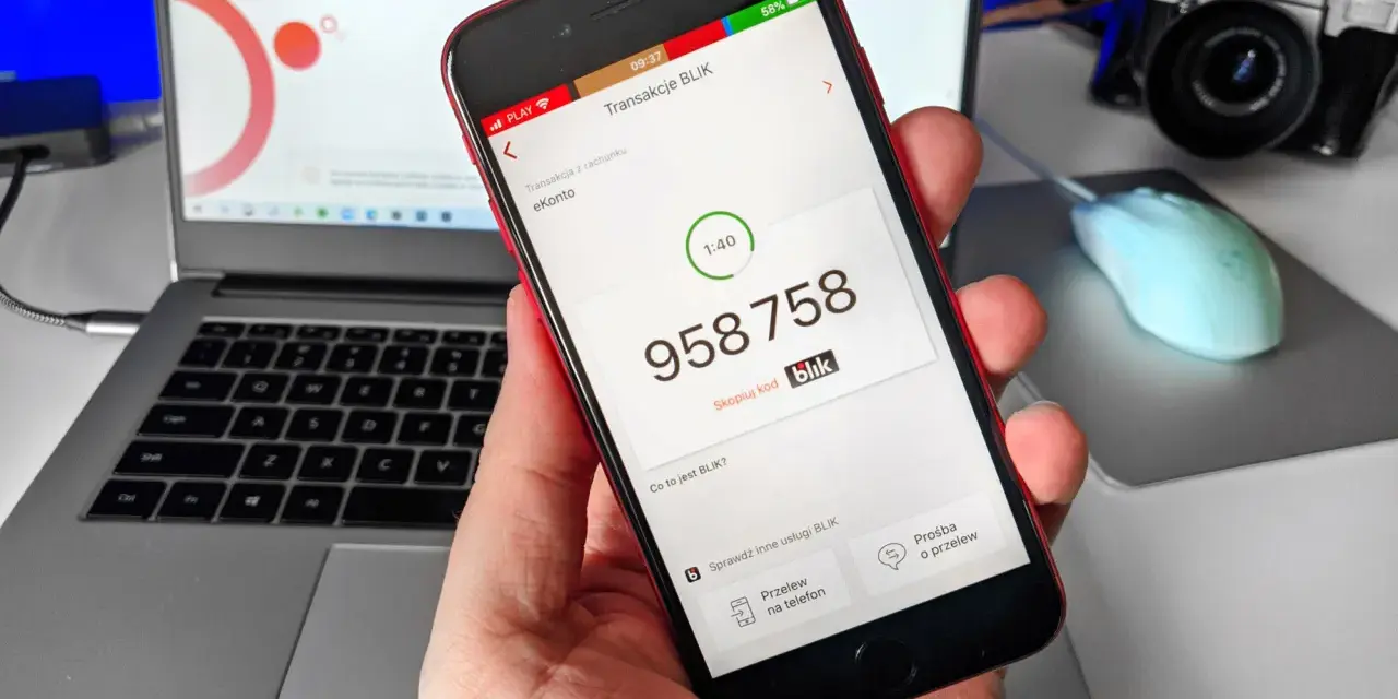 Dłoń trzyma smartfon z aplikacją Blik, na ekranie widoczny kod transakcji.