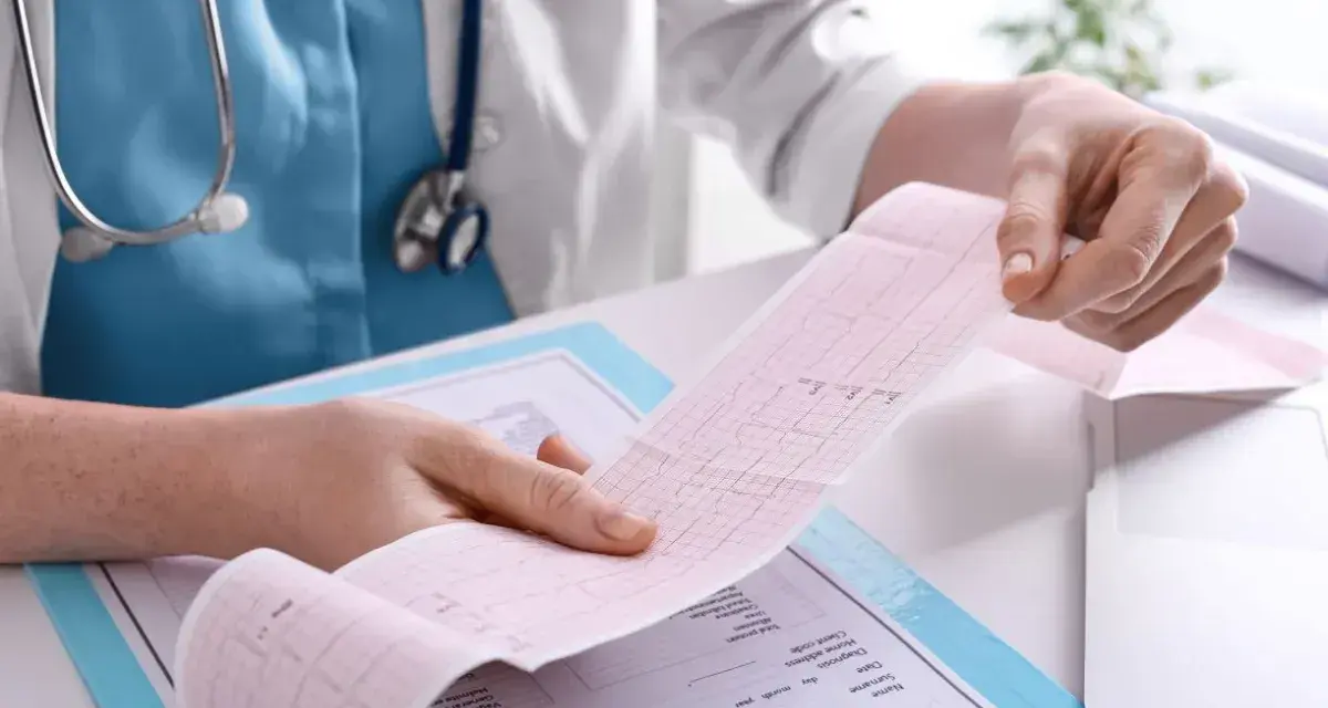 Lekarz analizuje wydruk EKG, pokazujący zapis pracy serca. To kluczowy element, jak się robi EKG i interpretuje wyniki.