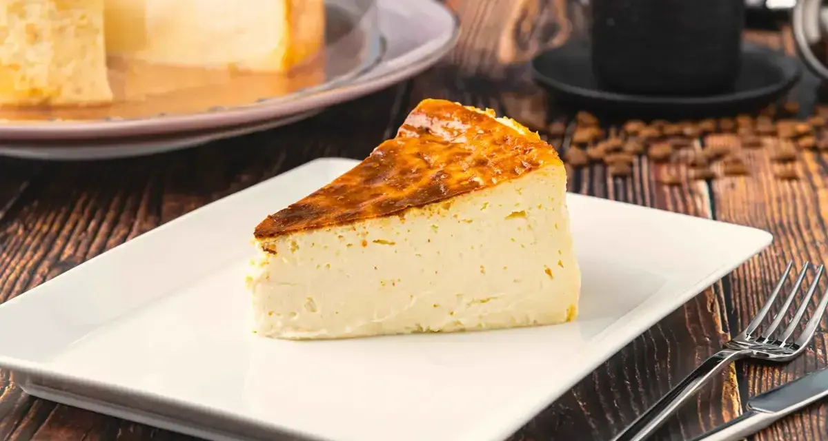Rebanada de tarta italiana mascarpone con corteza dorada, servida en plato blanco con cubiertos.