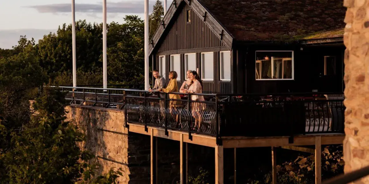 Vänner njuter av kvällssolen på balkongen vid Gyllene Utterns rastplats.