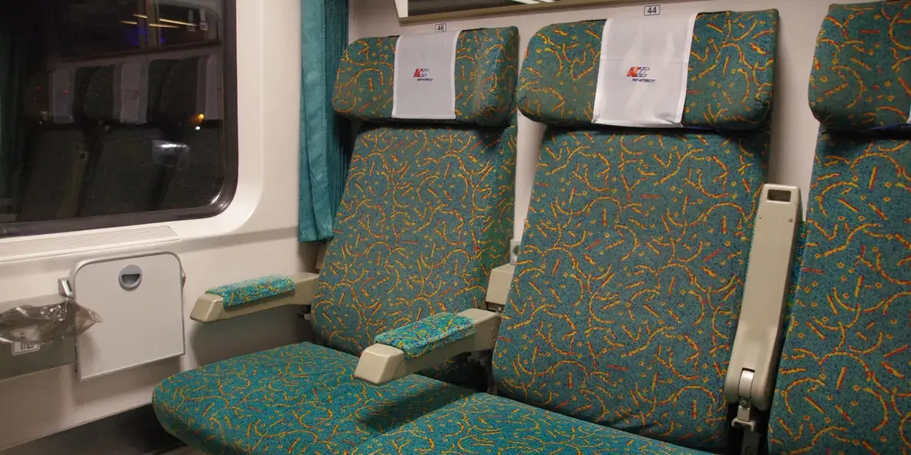 Wnętrze wagonu Intercity z zielonymi siedzeniami. Numer 46 nad zagłówkiem. Jak znaleźć wagon w pociągu Intercity?