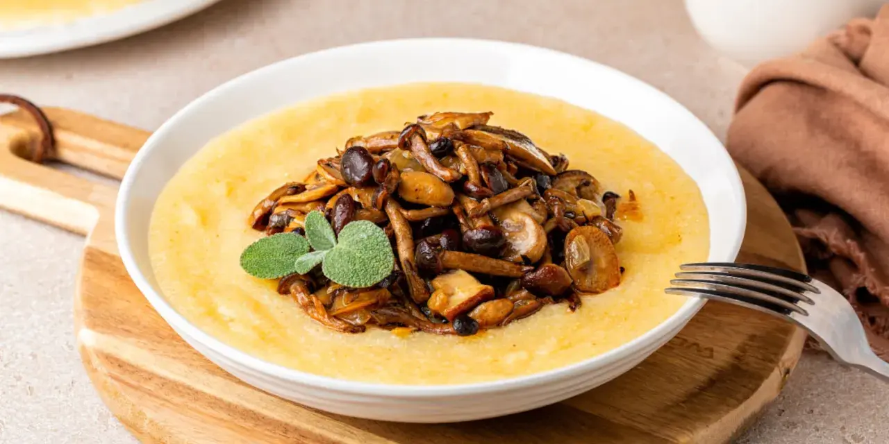 Polenta cremosa con champiñones salteados y una ramita de salvia. Un plato reconfortante que te hará preguntar: ¿polenta que es? ¡Deliciosa!