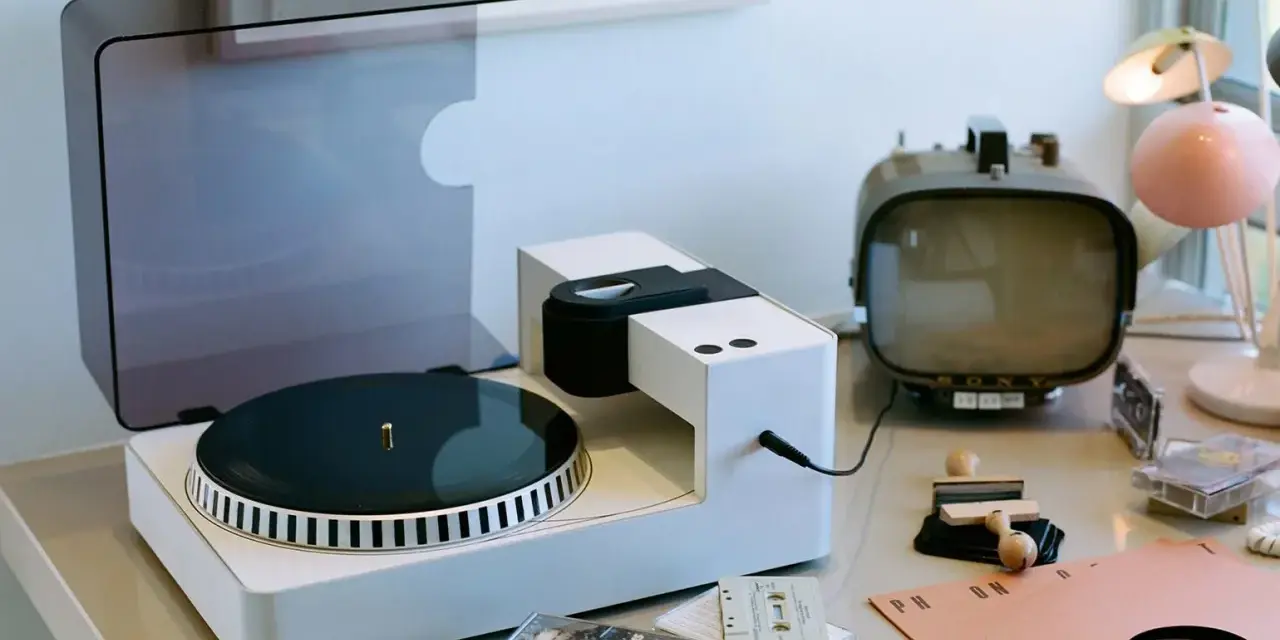 Moderner Plattenspieler mit Vinyl-Schallplatte, Kassetten und Retro-Fernseher. Hier wird die Frage "was ist Vinyl Musik" visuell beantwortet.
