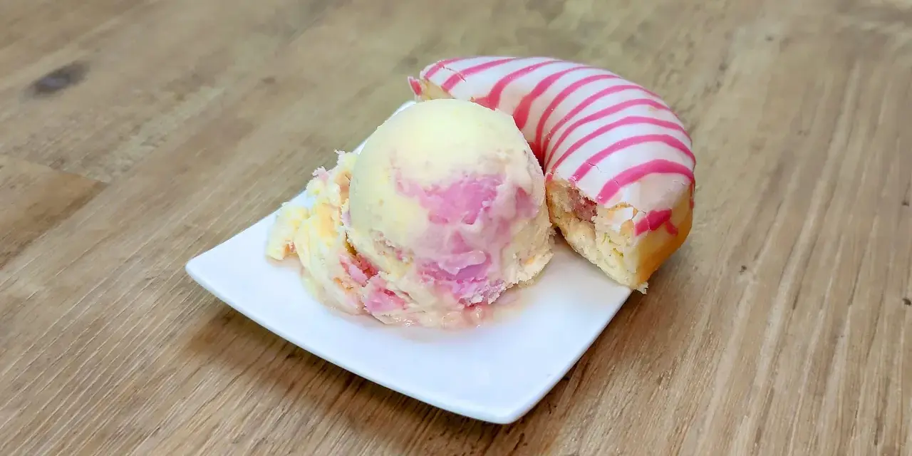Ein cremiges Eis mit rosa Schlieren neben einem Donut mit rosa Streifen. Perfekt für eine süße Auszeit!