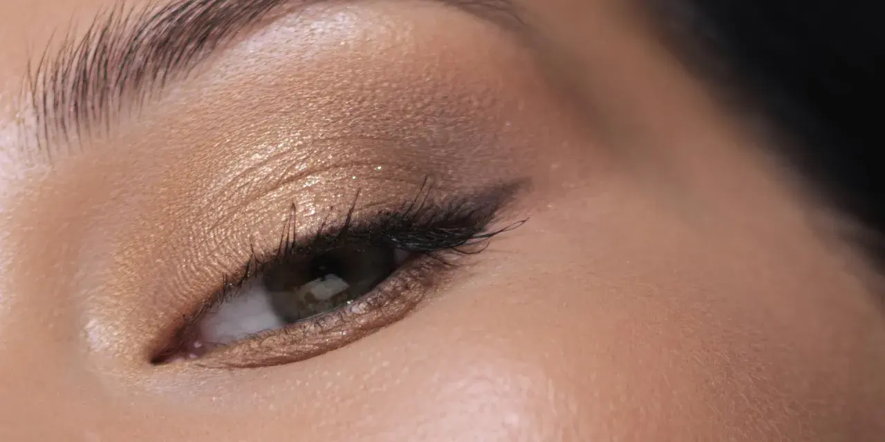 Maquillage paupière tombante : ombre dorée scintillante, trait d'eye-liner fin et cils longs pour un regard sublimé.