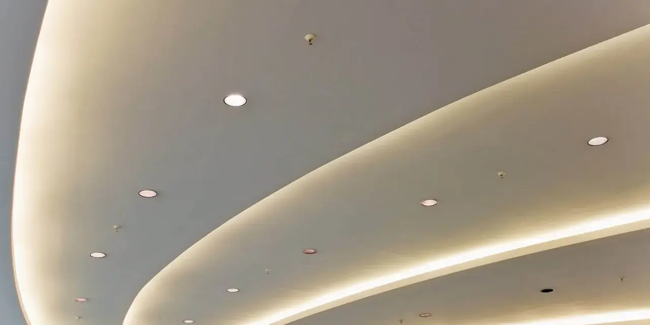 Nowoczesny podwieszany sufit z ukrytym oświetleniem LED tworzy łagodne, faliste linie, dodając przestrzeni elegancji.