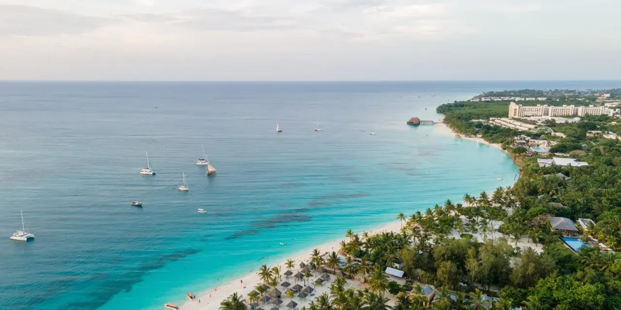 Rajska plaża na Zanzibarze z turkusową wodą, łodziami i luksusowymi hotelami. Sprawdź Zanzibar ceny i zaplanuj wymarzone wakacje!