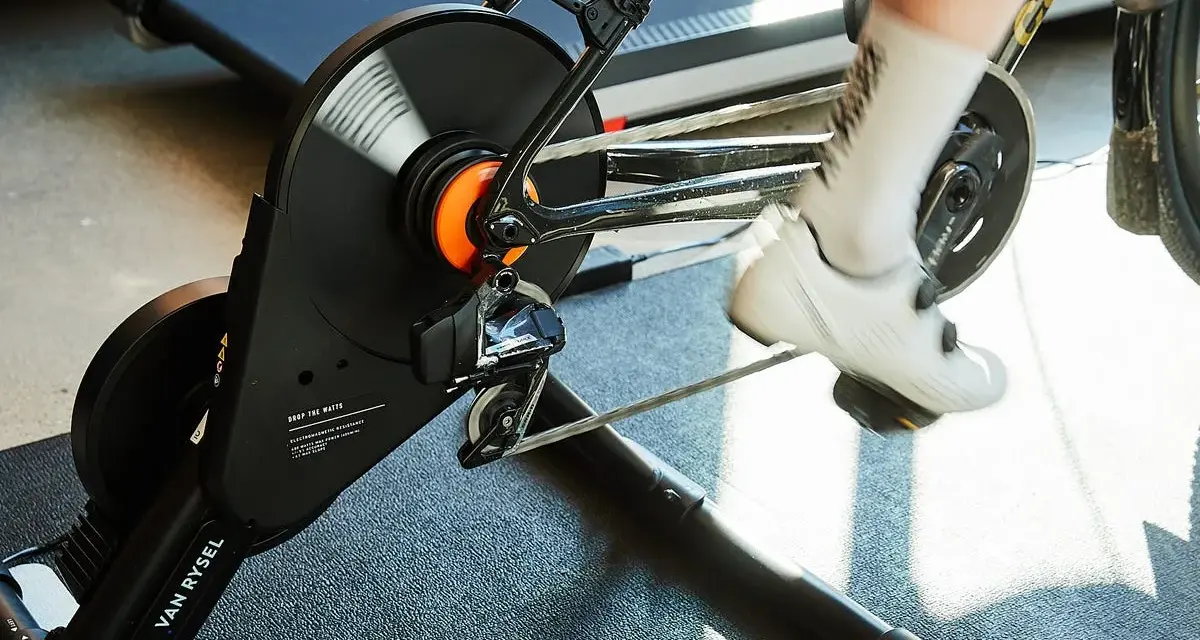 A cyclist's feet pedal on a bike connected to a magnetic resistance trainer, ready for an indoor workout.