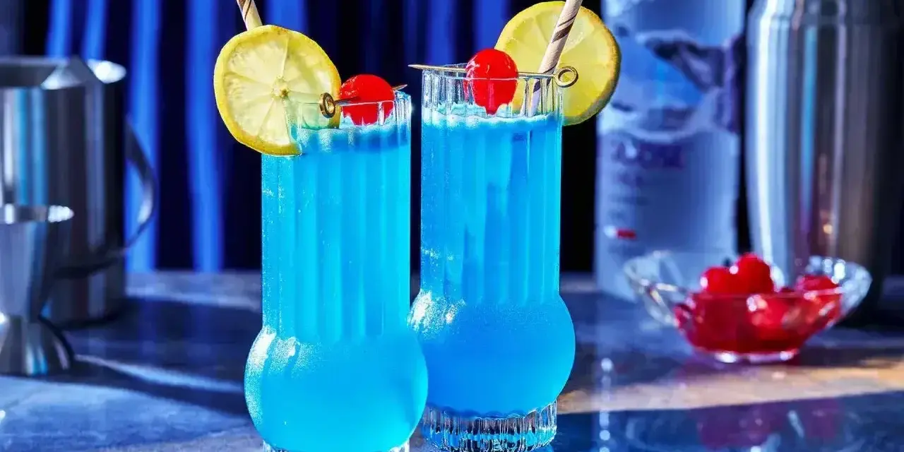 Dwa błękitne drinki Kamikaze, ozdobione cytryną i wiśnią, idealne do picia w letni wieczór.