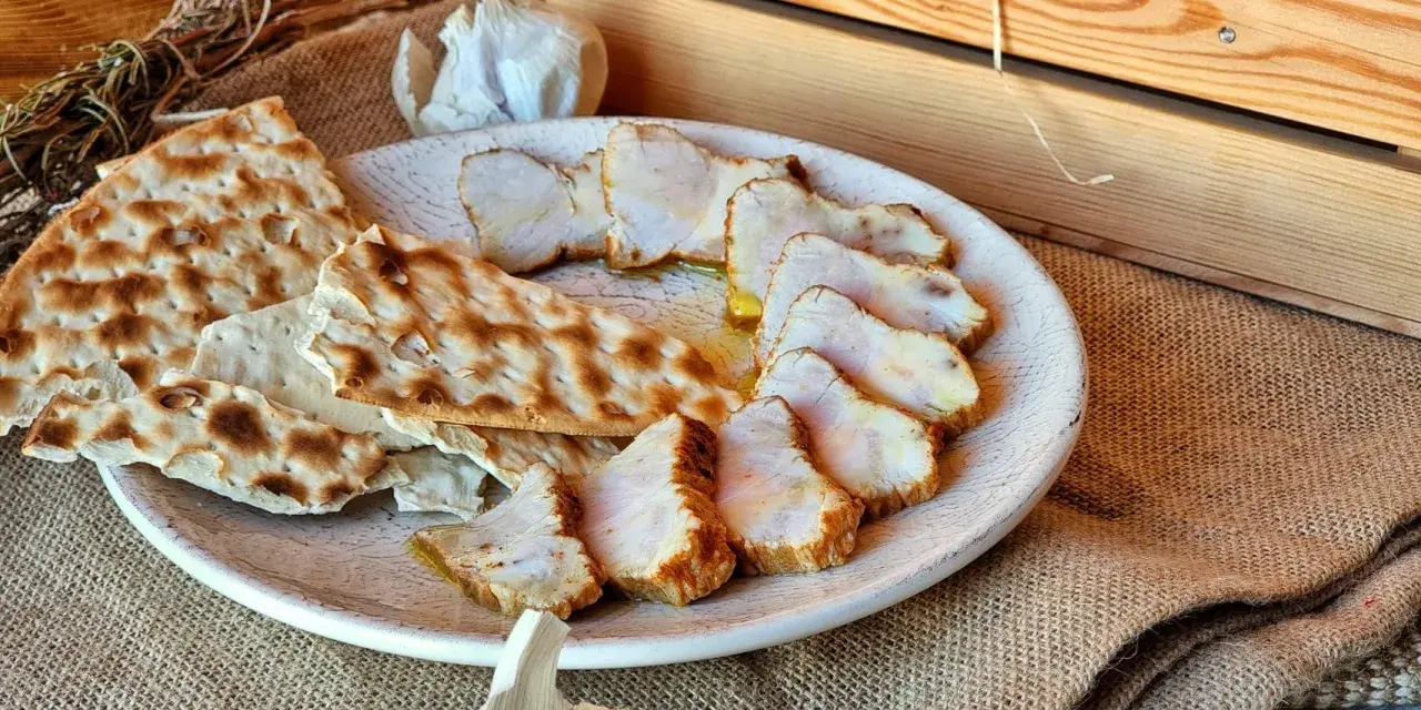 Lomo de orza en rodajas, servido con pan crujiente y ajo. Un plato rústico y delicioso.
