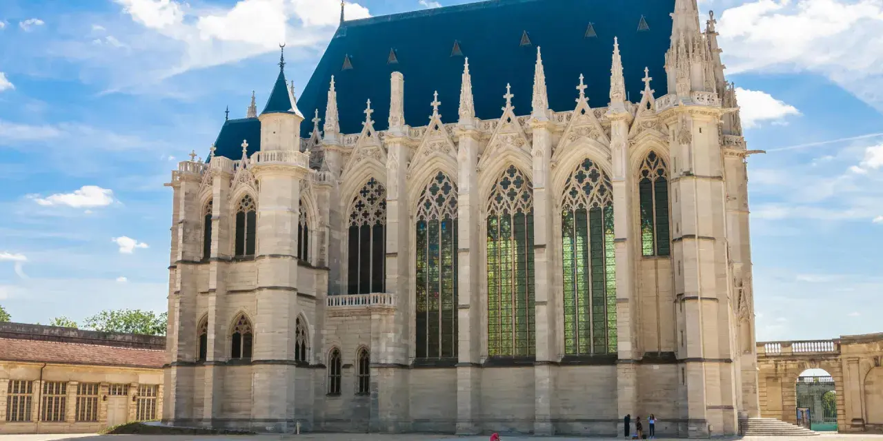 The stunning Sainte-Chapelle in Paris, with its Gothic architecture and vibrant stained-glass windows, stands majestically under a bright blue sky.