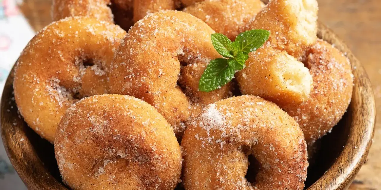 Rosquillas de la abuela esponjosas, cubiertas de azúcar y canela, con una ramita de menta. ¡Un placer casero!