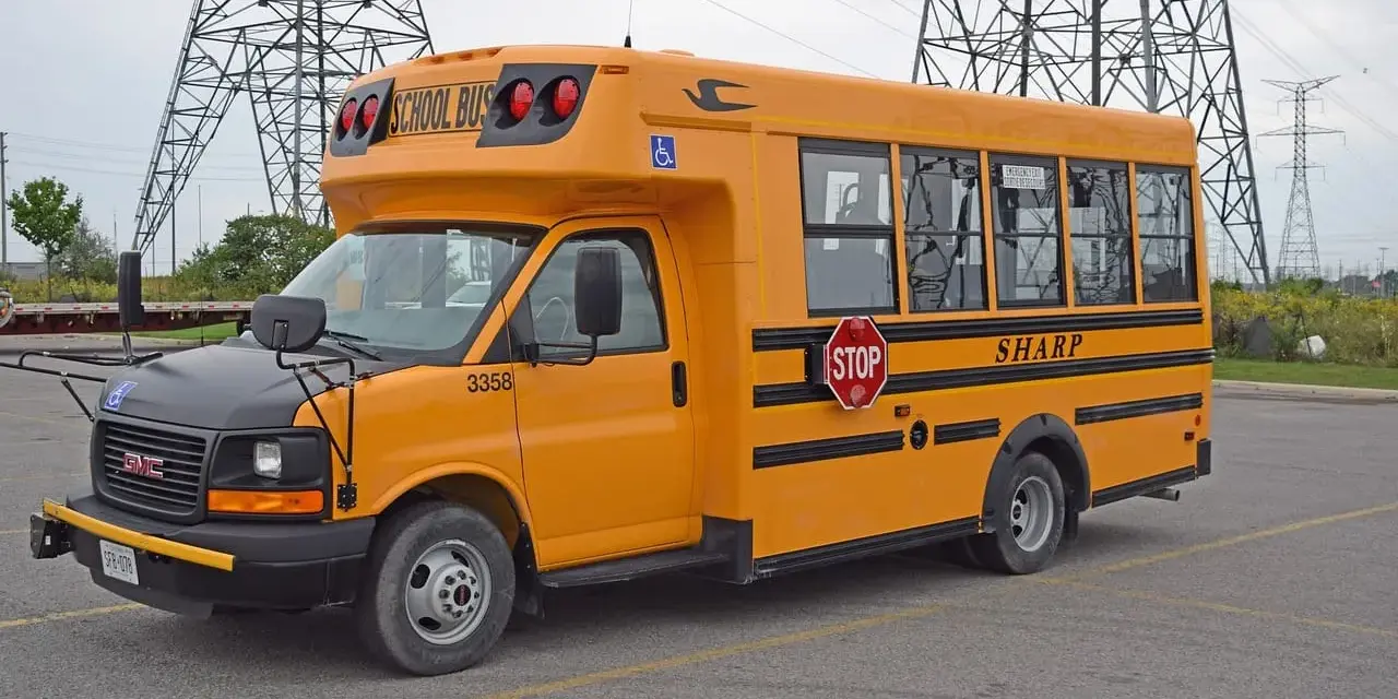 Żółty autobus szkolny GMC z napisem "SHARP" i znakiem STOP. Zastanawiasz się, ile kosztuje autobus?