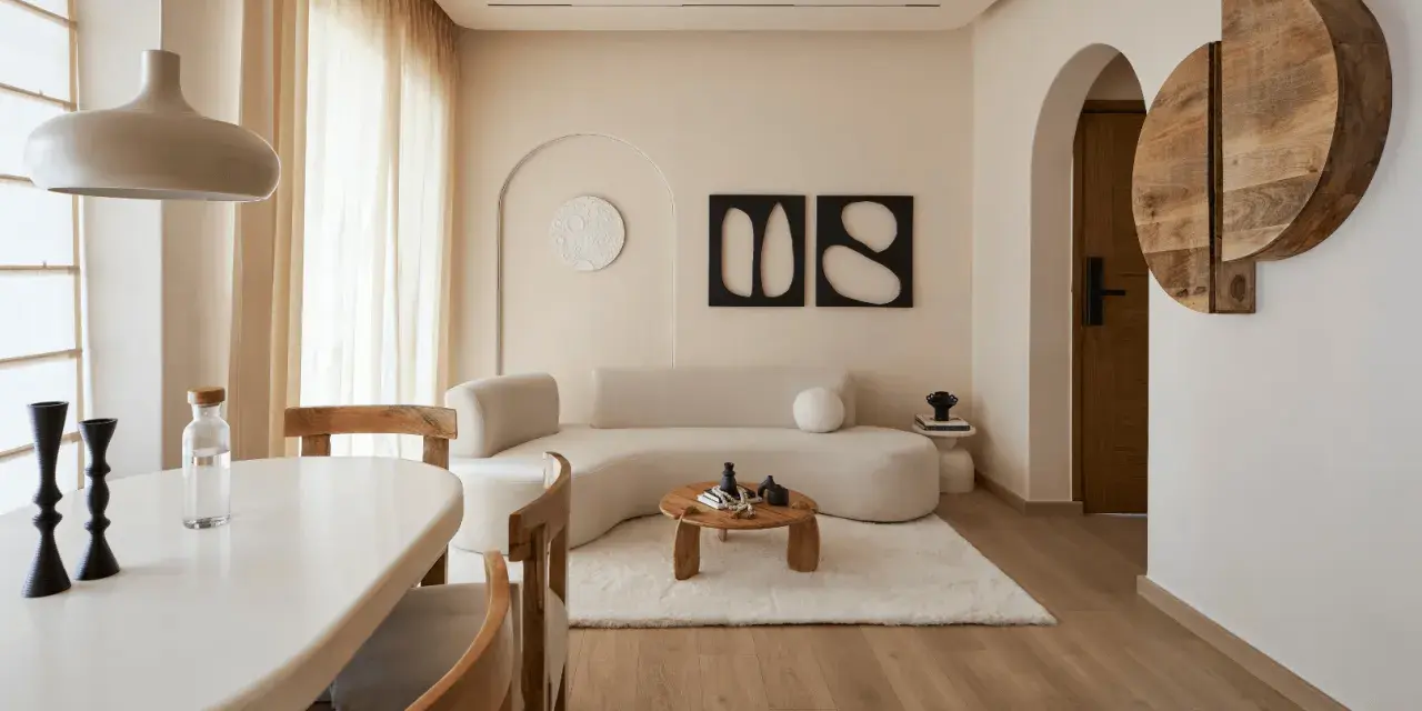 Un soggiorno in stile wabi sabi arredamento, con divano curvo, tavolino in legno grezzo, tappeto soffice e decorazioni organiche.