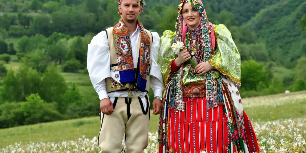 Para w tradycyjnych strojach na tle zielonych wzgórz. Ciekawe albania ciekawostki o kulturze i tradycji.