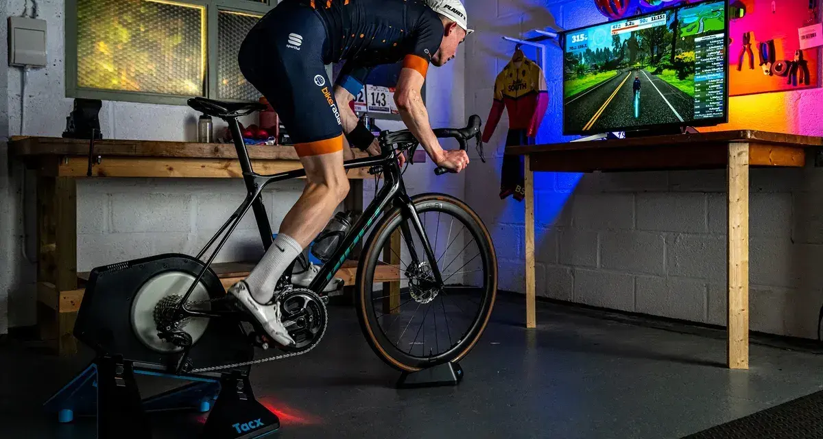A cyclist trains indoors on a bike trainer, with a screen showing a virtual road. This setup demonstrates how to set up a bike trainer for immersive cycling.