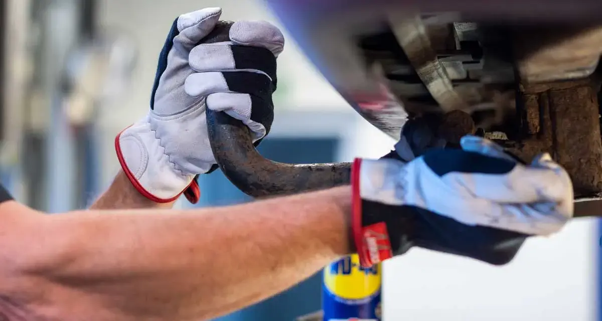 Händer med handskar som arbetar med en dragkrok, kanske för att ta bort dragkrok inför besiktning.
