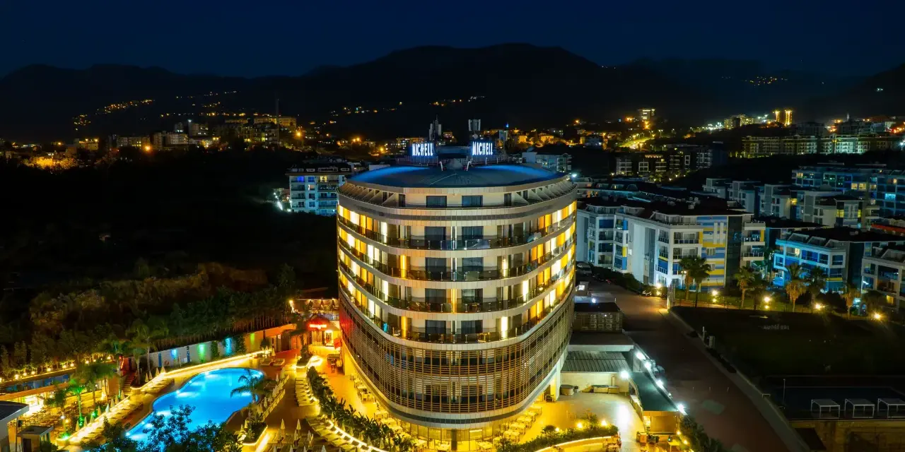 Nocny widok na lśniący hotel Michell z basenem i oświetlonymi pokojami. Wiele pozytywnych michell hotel spa opinie potwierdza jego urok.