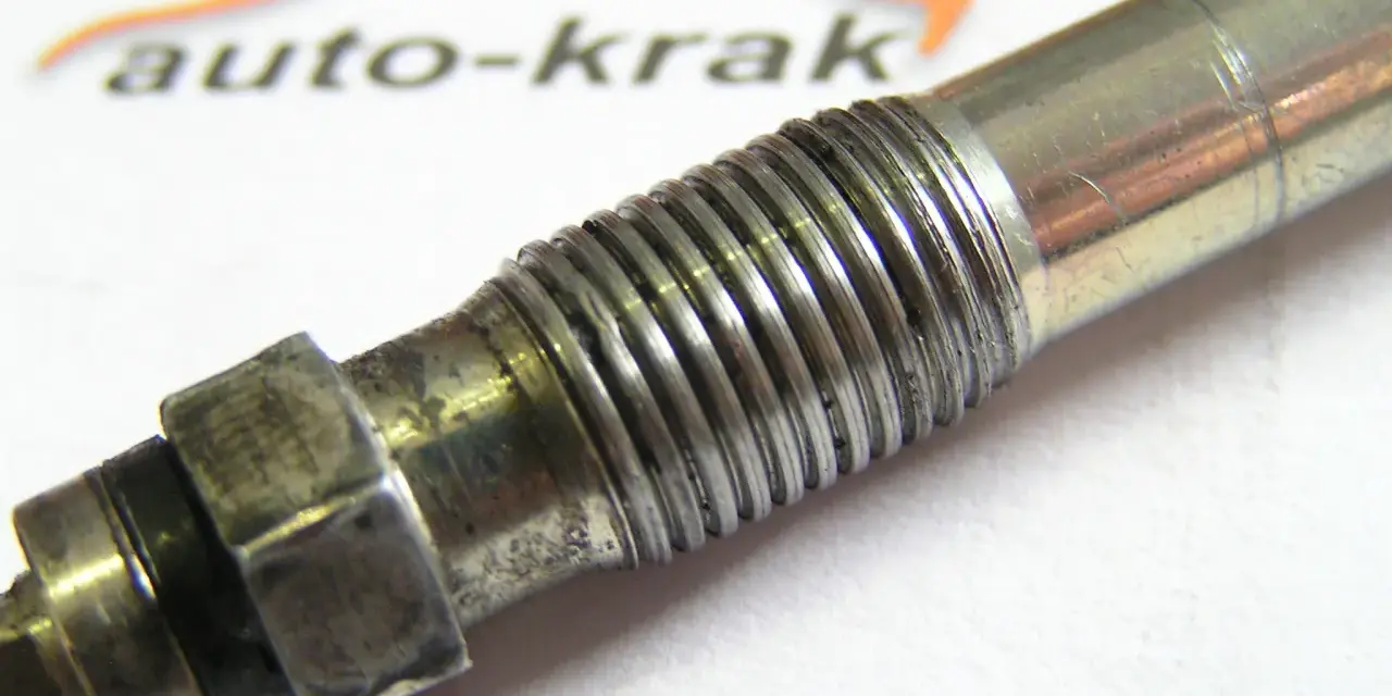 Metalowa, urwana świeca żarowa z widocznym gwintem i sześciokątnym mocowaniem.