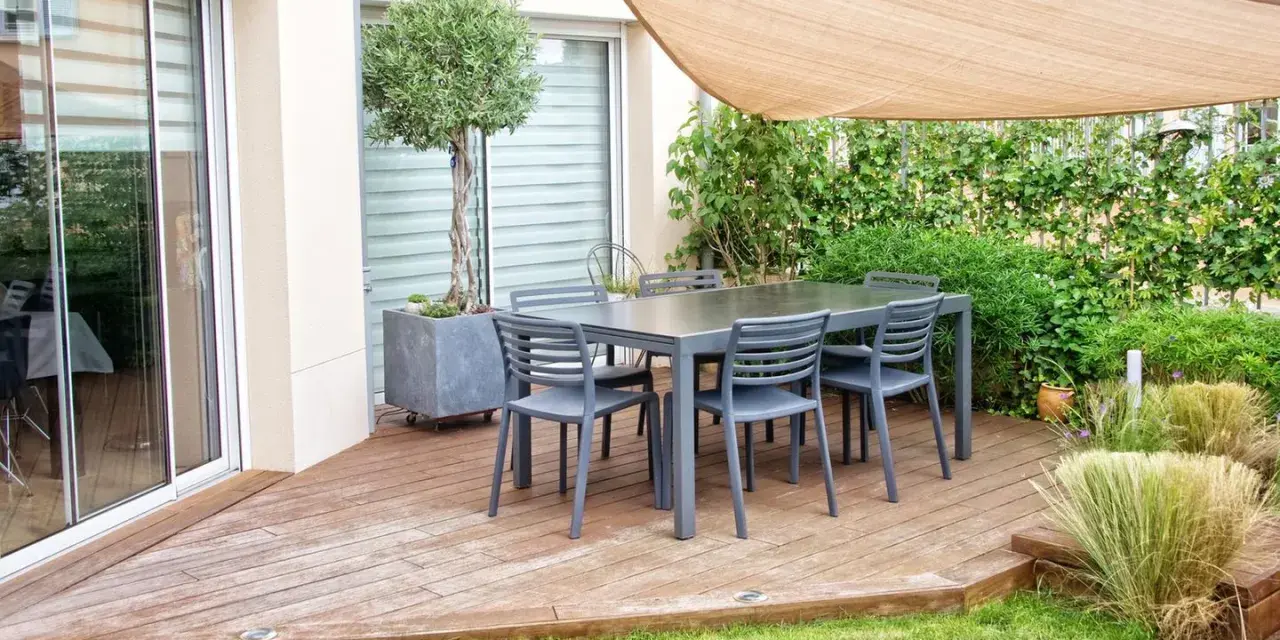Terrasse mit Tisch und Stühlen, Sonnensegel und üppiger Bepflanzung. Tolle selber balkon sichtschutz ideen für Privatsphäre.