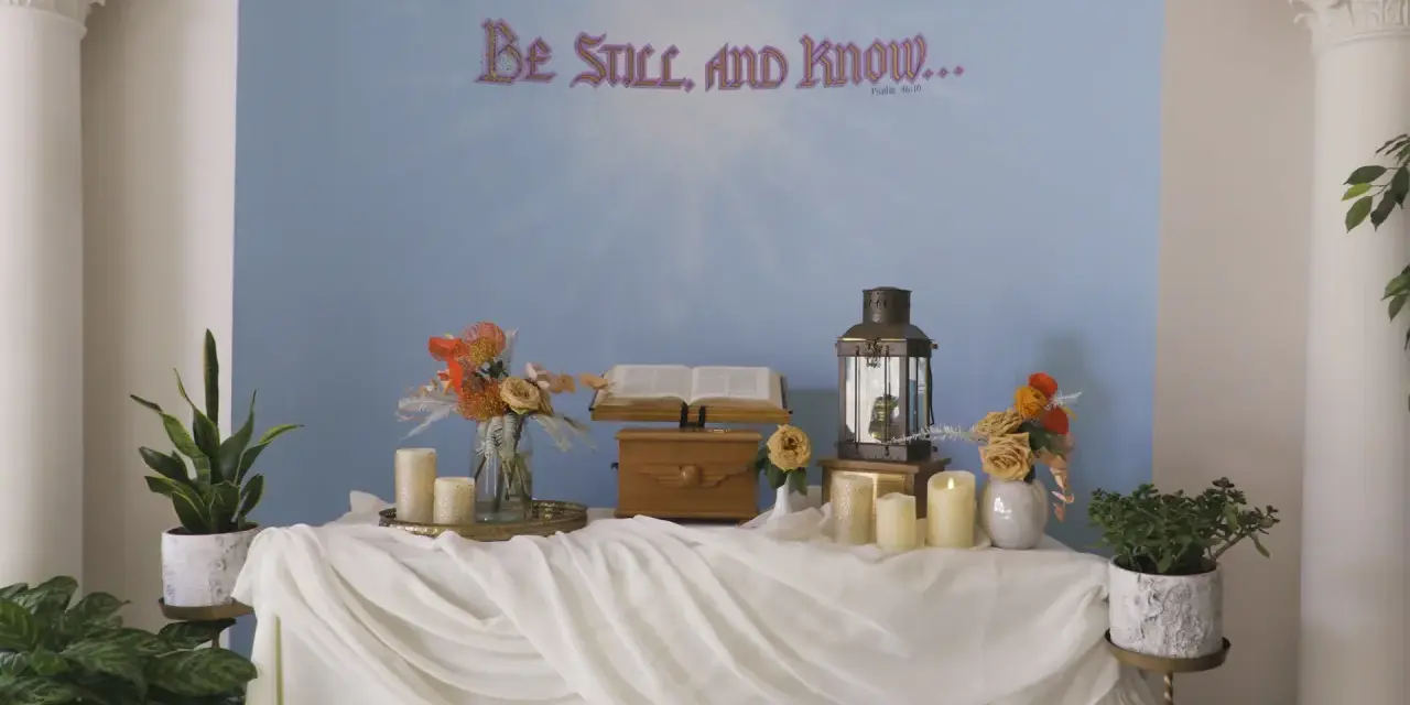 A serene scene for a midnight vigil: an open Bible, a lantern, and candles on a draped table, with "Be Still, and Know..." on the wall.