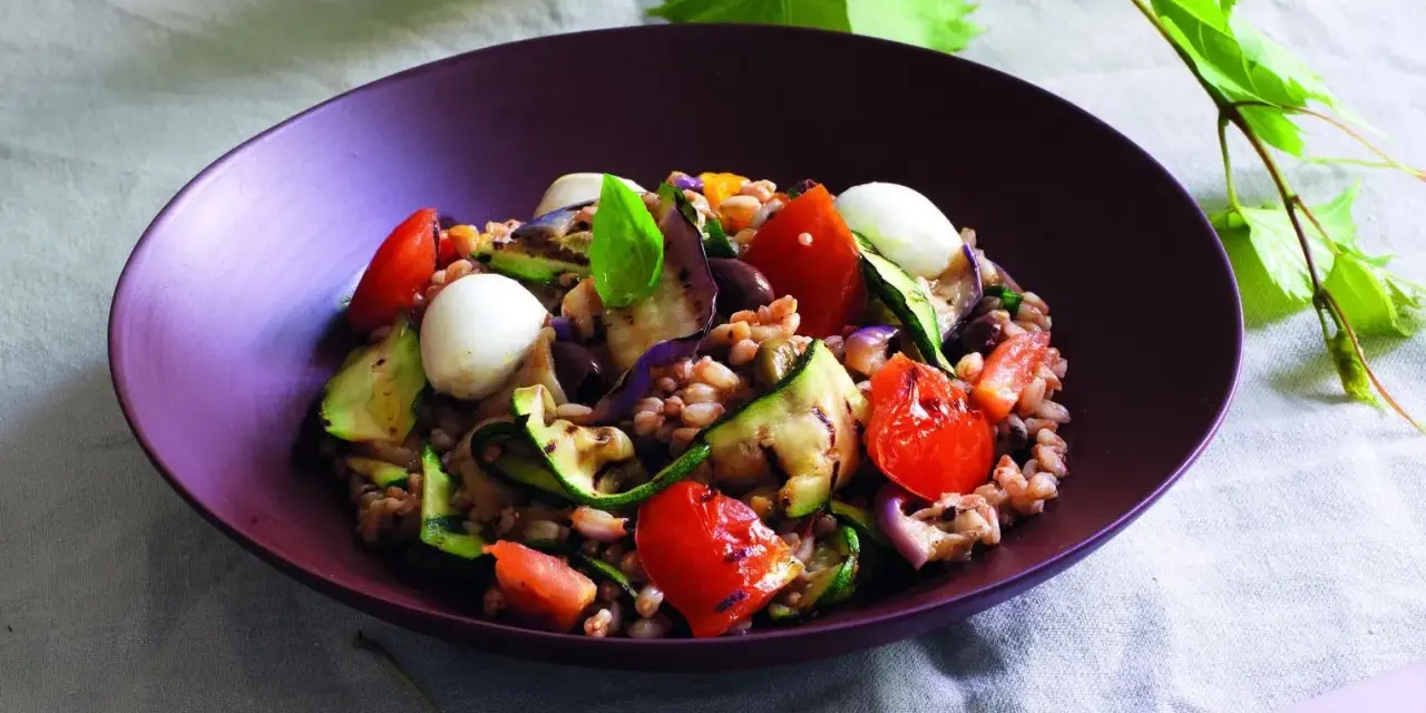 Insalata di farro estiva con verdure grigliate, pomodorini, mozzarelline e basilico fresco.