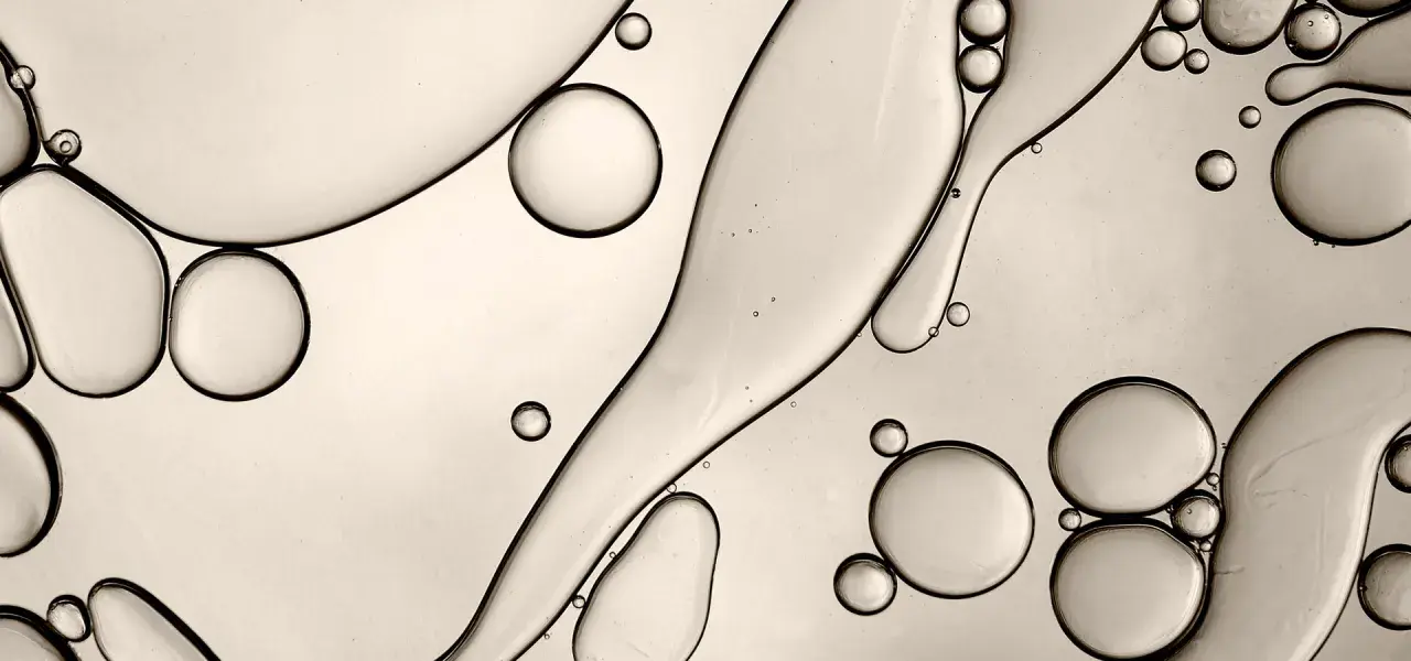 Gocce d'olio e acqua creano forme astratte, ricordando la struttura di un c13-15 alkane.