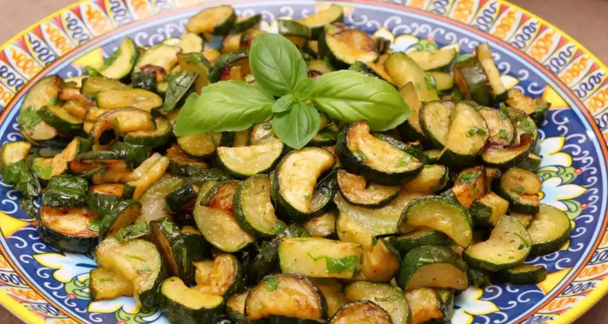 Zucchine trifolate dorate e saporite, guarnite con basilico fresco, servite su un piatto decorato.