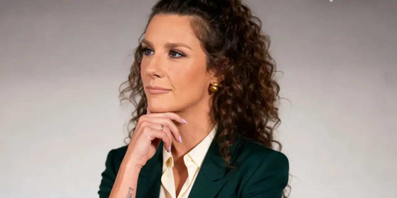 Wiolka Walaszczyk, w wieku około 40 lat, w eleganckim zielonym żakiecie, zamyślona.