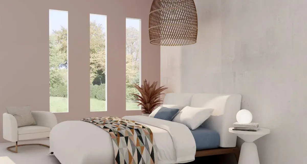 Habitación con cama blanca y manta geométrica. Tres ventanas verticales dejan ver un jardín. El espacio, con tonos neutros, evoca la serenidad de los cuartos blancos.