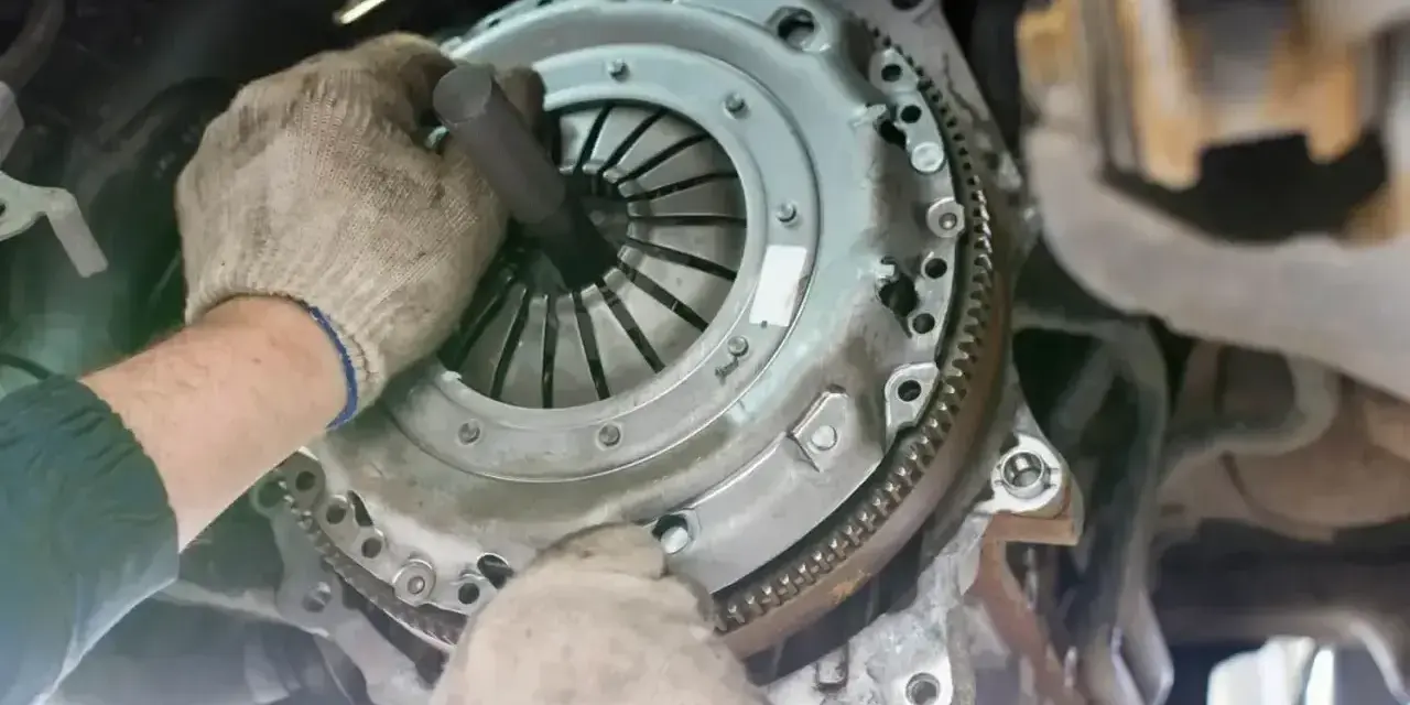 Mechanik w rękawiczkach montuje tarczę sprzęgła, przygotowując wysprzęglik sprzęgła do pracy.