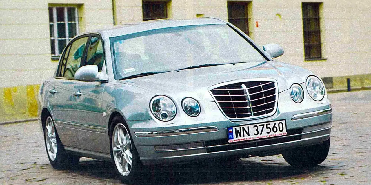 Srebrny Kia Opirus z polskimi tablicami rejestracyjnymi WN 37560 na brukowanej ulicy.